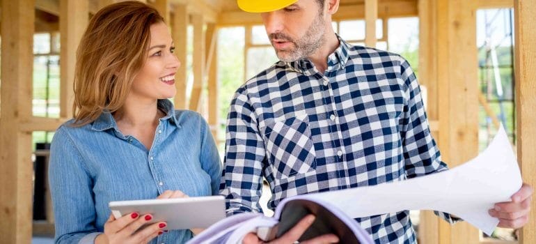 Female homeowner consults blueprints with Architec