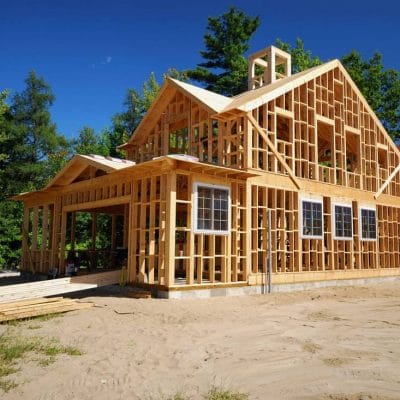 A-wooden-framing-of-a-house-under-construction-with-trees-on-the-background wooden framing House